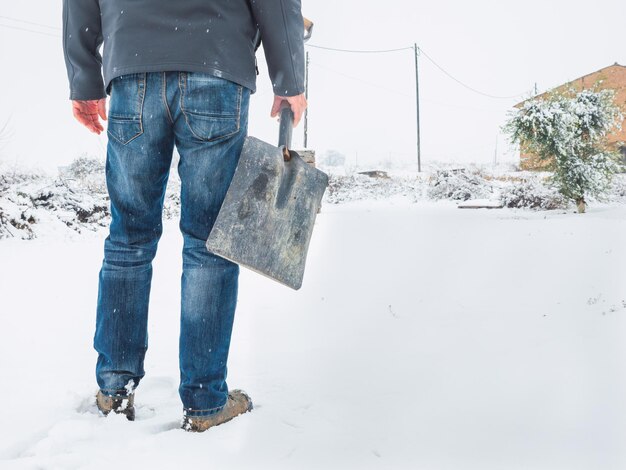 吹雪の後、トレイルから雪を取り除くためにシャベルを持った男。冬のコンセプト