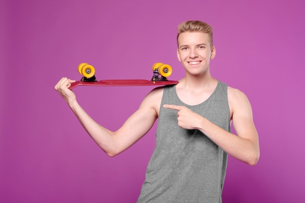 Man with skate board in hand on purple background, penny little board