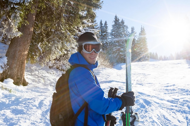 A man with skis stands in the snow.