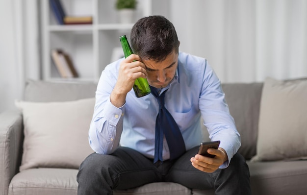 Мужчина со смартфоном и бутылкой пива дома