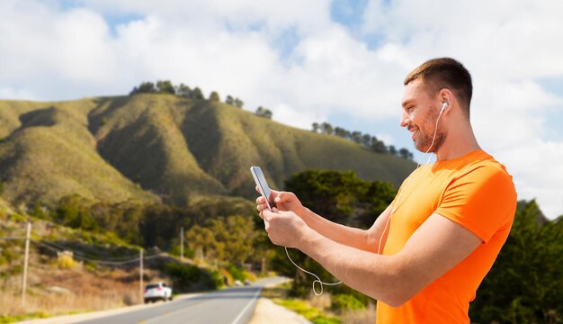 man with smartphone and earphones over big sur