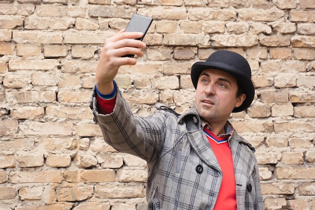 A man with a smartphone in his hands against a background of a brick wall