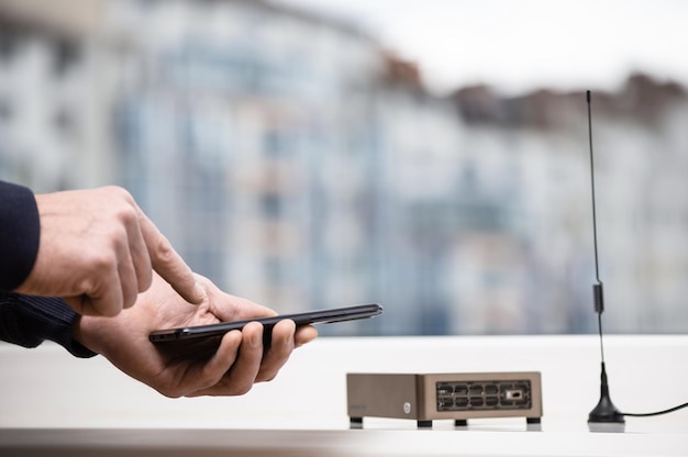 Photo a man with a smartphone is setting up a wireless hotspot for helium token mining