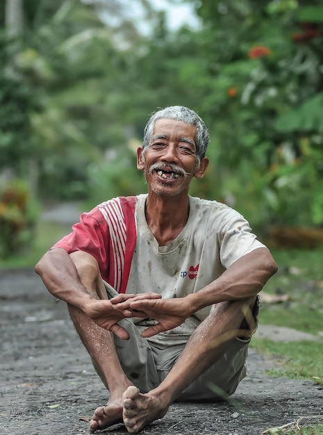 A man with a smile on his face is sitting on a path.