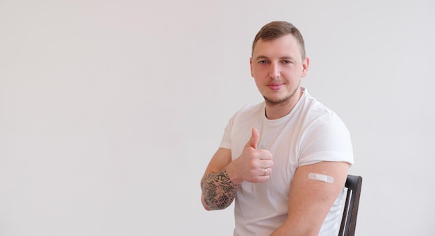 Мужчина с улыбкой на лице показывает марку вакцины на белом фоне