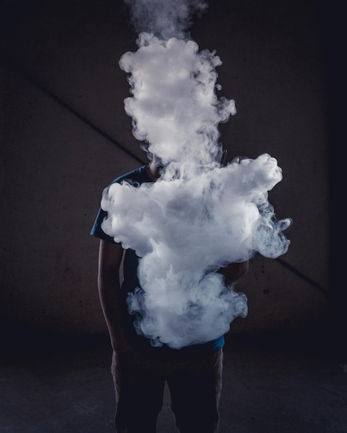 Man with smoke standing in darkroom