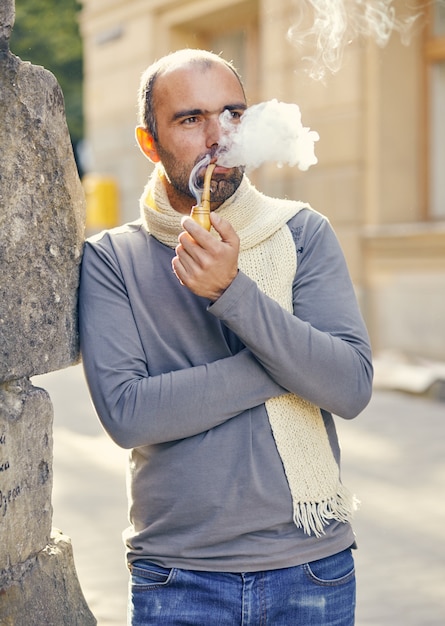 Photo man with a smoking pipe. bearded handsome young man holding a smoking pipe