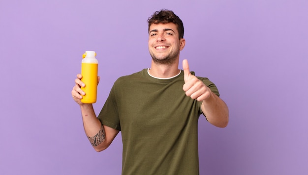 Man with smoothy feeling proud, carefree, confident and happy, smiling positively with thumbs up