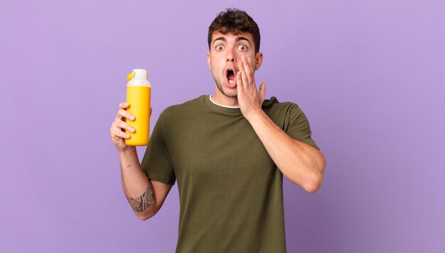 man with smoothy feeling shocked and scared, looking terrified with open mouth and hands on cheeks