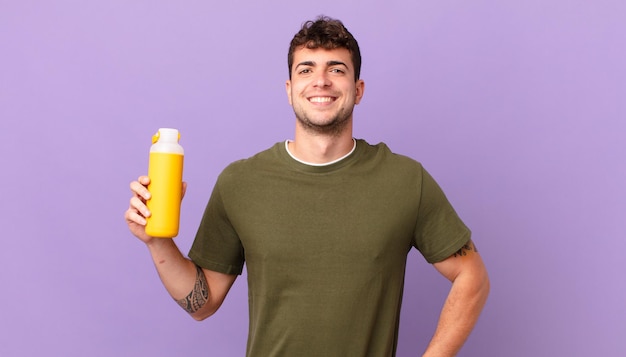 Man with smoothy smiling happily with a hand on hip and confident, positive, proud and friendly attitude