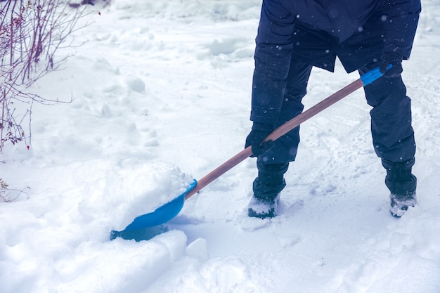 雪かきを持った男が冬に道路を掃除します。降雪後に雪かきをする男