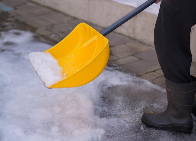 雪かきを持った男が冬に歩道を掃除します。冬時間。