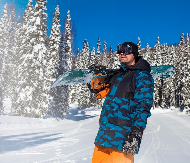 A man with a snowboard in his hands outdoors against the background of the forest