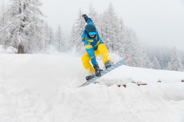 Foto l'uomo con lo snowboard che salta e che fa i trucchi sulla neve