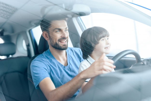 Man with son smiles and drive a car.