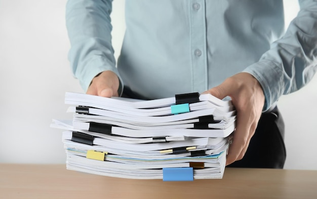 Man with stack of documents against light background