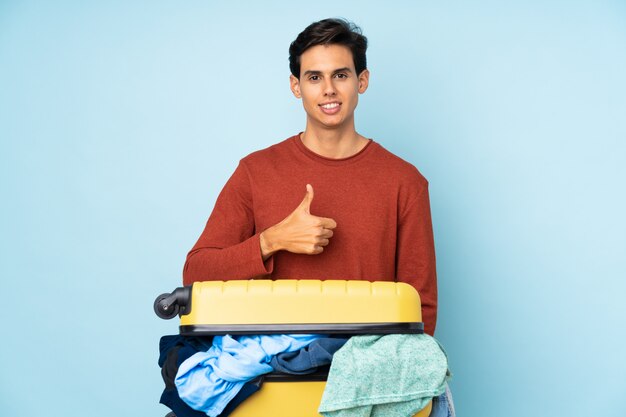 Man with a suitcase full of clothes giving a thumbs up gesture