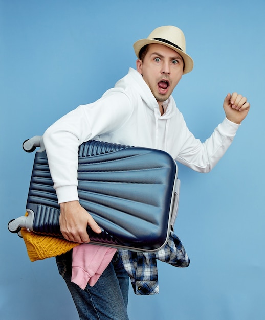 スーツケースを持った男が飛行機に急いで、荷物から物事が落ちる