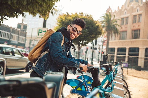 Man with sunglasses smiles while getting ready to ride a bike in the city