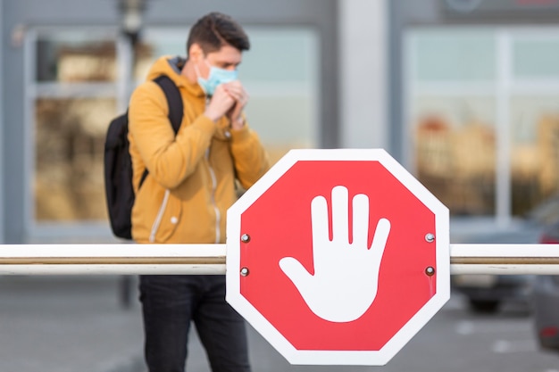 Foto uomo con maschera chirurgica e segnale di stop