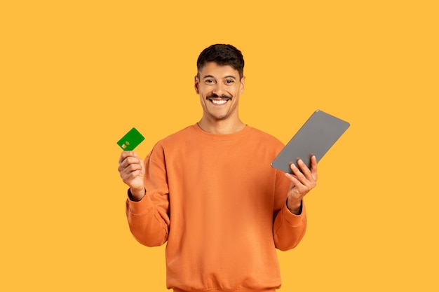 Man with tablet and credit card on yellow