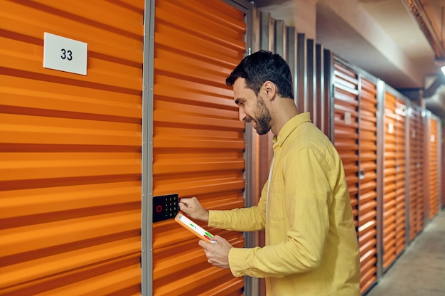 Man with tablet near combination lock of garage door