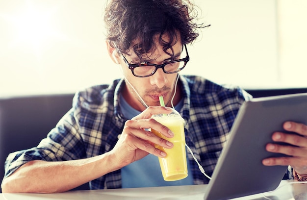 man with tablet pc and earphones sitting at cafe