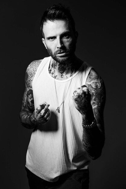 Photo a man with tattoos on his arms is wearing a white tank top.