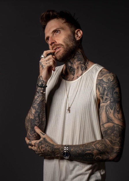 Photo a man with tattoos on his arms looks at the camera