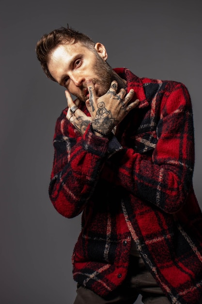 A man with tattoos on his face and a red plaid jacket.