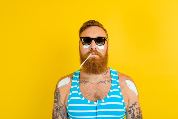 Man with tattoos and swimsuit puts on sunscreen