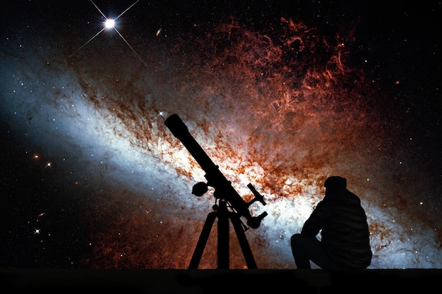 망원경으로 별을 바라보는 남자. 이 이미지의 별자리 Ursa Major Elements의 Messier 82, Cigar Galaxy 또는 M82는 NASA에서 제공한 것입니다.