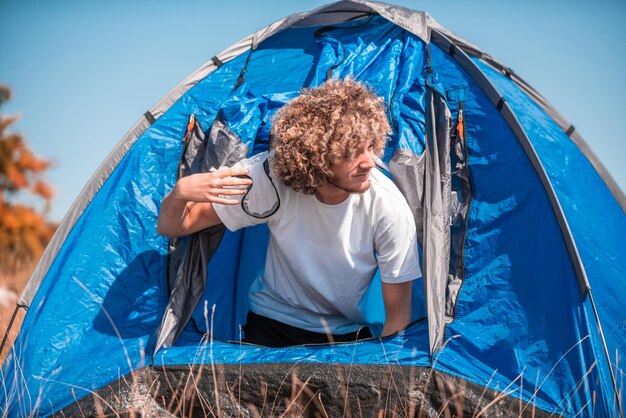 Photo a man with a tent enjoys a sunny day whileusing a smartphone and camping in the mountains