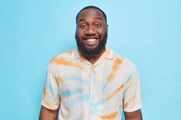  man with thick beard smiles broadly has white perfect teeth dressed in washed out t shirt poses 