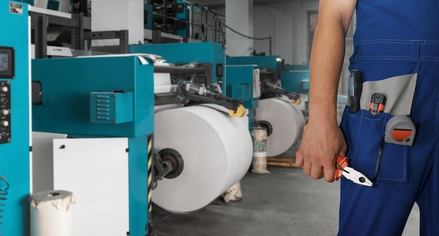 Man with tool box working in printing house with an printing machine