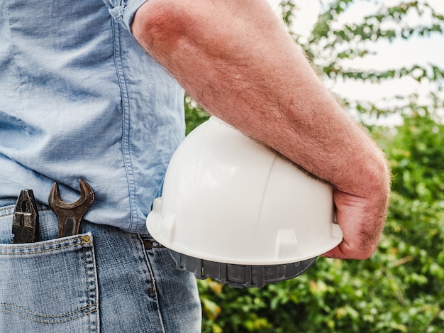 Man with tools holding a safety helmet