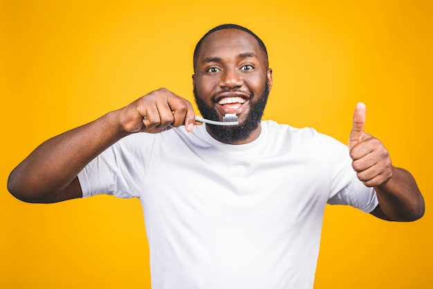 Uomo con spazzolino da denti. immagine di giovane uomo africano senza camicia in possesso di uno spazzolino da denti con dentifricio e sorridente pollice in alto.