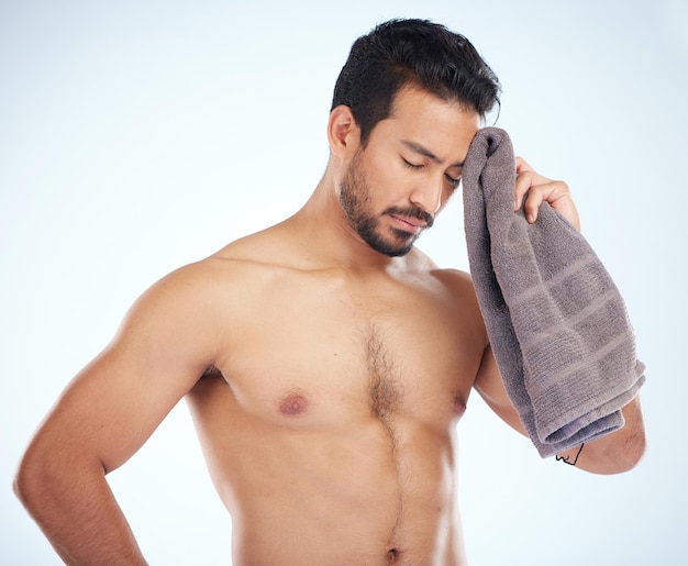 Man with towel after fitness tired and sweat from workout with health and body care against studio background Sports training motivation and exhausted athlete wipe head with wellness and cardio