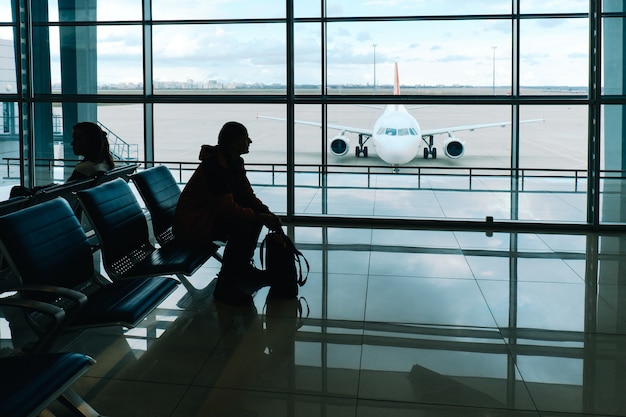 공항 터미널 라운지에서 탑승을 기다리는 여행 배낭을 가진 남자