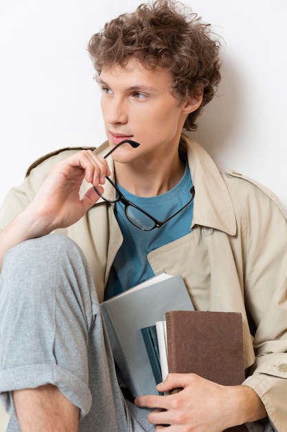 Man with trench coat holding books