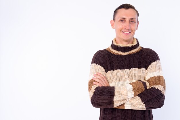 Uomo con maglione a collo alto pronto per l'inverno isolato contro il muro bianco