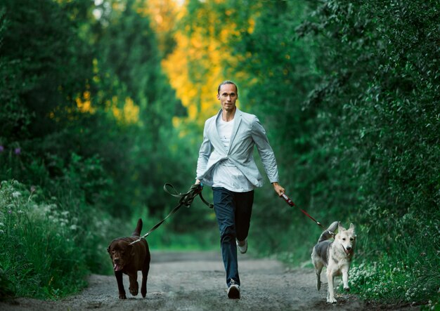 Un uomo con due cani che cammina su un prato soleggiato