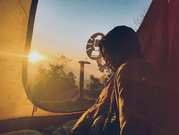 Foto uomo con l'ombrello contro il cielo durante il tramonto