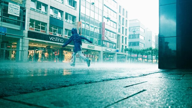 写真 雨の中れた通りで傘をかぶった男