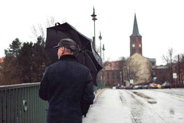 Man with umbrella walking in city during winter