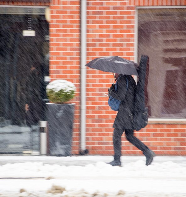 Photo man with umbrella walking down the street in winter day in motion blur. defocused image