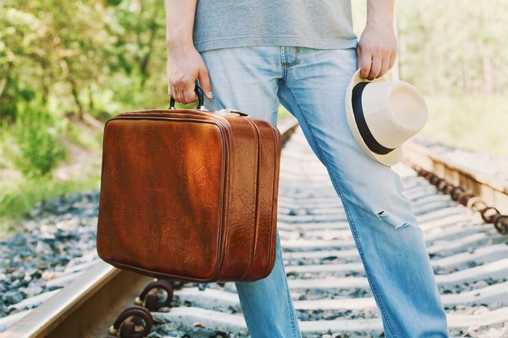 Photo ヴィンテージのスーツケースと帽子をかぶった男が ⁇ 晴れた日に鉄道に立っています ⁇ 休日 ⁇ 休暇旅行