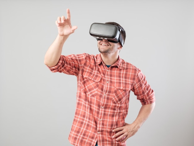 Человек в очках виртуальной реальности показывает жест на сером фоне