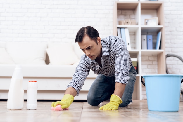 Man with Washcloth Cleaning Floor in Apartment.