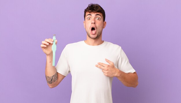 Man with a watch looking shocked and surprised with mouth wide open, pointing to self